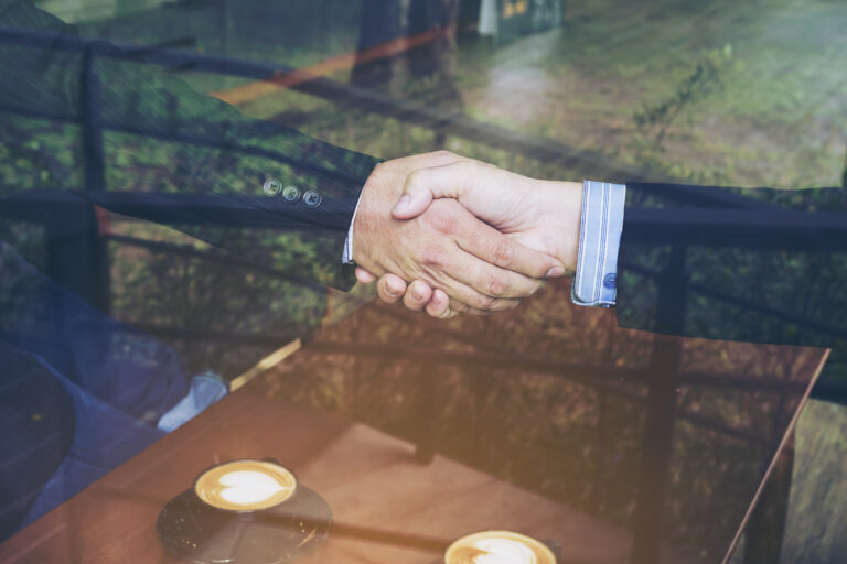 Two businessman shake hand in coffee shop